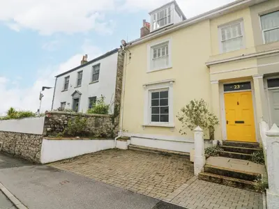 a white house with a yellow door on a street at The Water House in Falmouth