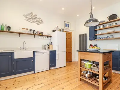 a kitchen with blue cabinets and a white refrigerator at The Water House in Falmouth