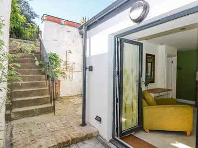 an open door to a house with a yellow chair at The Water House in Falmouth