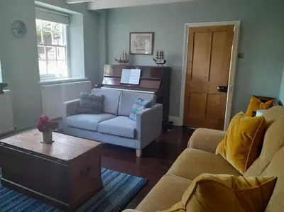 a living room with a couch and a piano at The Captain's House Charlestown St Austell in Charlestown