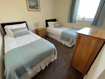 a bedroom with two beds and a window at Lovely 2 Bedroom flat moments from Fistral Newquay in Newquay
