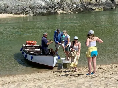 a group of people standing on the beach next to a boat at Lovely 2 Bedroom flat moments from Fistral Newquay in Newquay