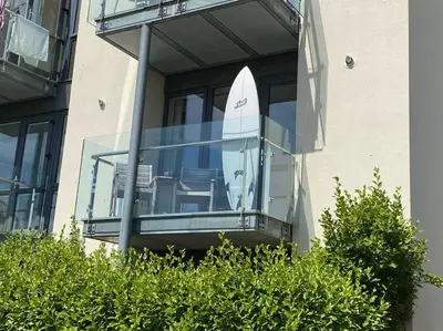 a glass balcony with a surfboard inside of a building at Lovely 2 Bedroom flat moments from Fistral Newquay in Newquay