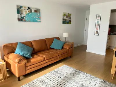 a living room with a brown couch and blue pillows at Lovely 2 Bedroom flat moments from Fistral Newquay in Newquay