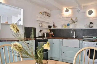 a kitchen with a table with a vase of flowers at Sunny Corner in Port Isaac