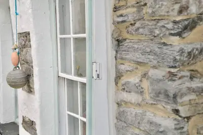 a window on a stone wall next to a door at Sunny Corner in Port Isaac
