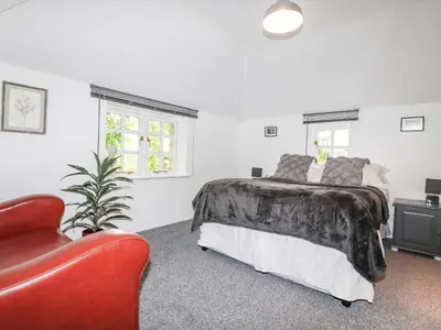 a bedroom with a bed and a red chair at The Cottage in Bodmin