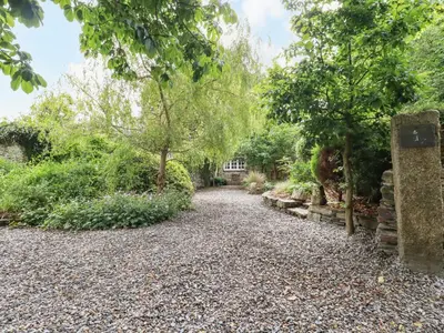 a gravel driveway in a garden with trees at The Cottage in Bodmin