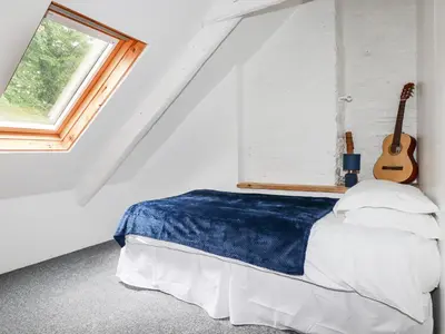a bedroom with a bed with a guitar next to a window at The Cottage in Bodmin