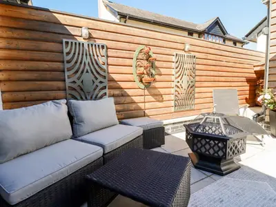 a patio with a couch and a table and a fence at Clonmore in Bodmin