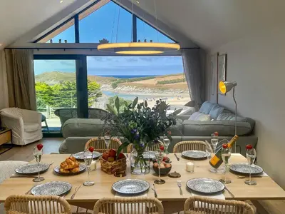 a dining room table with a view of the ocean at Porth Beach in Newquay