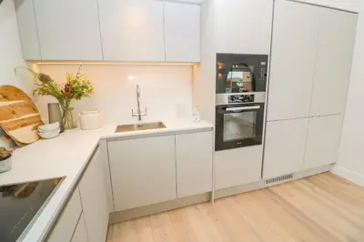a kitchen with white cabinets and a sink at Porth Beach in Newquay