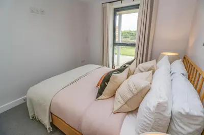 a bedroom with a bed with pillows and a window at Porth Beach in Newquay