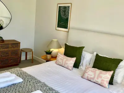 a bedroom with a white bed with green pillows at Porth Beach in Newquay