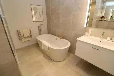 a white bathroom with a tub and a sink at Porth Beach in Newquay