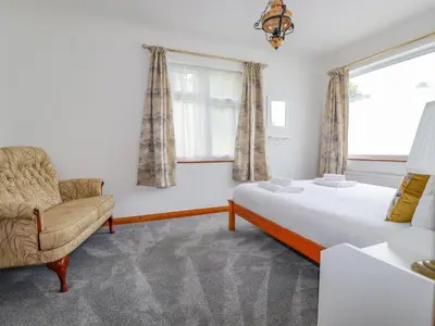 a bedroom with a bed and a chair and a window at Pen-Y-Thon House in Newquay