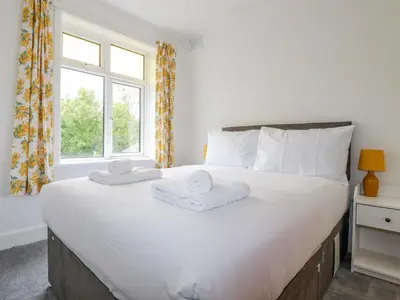 a bedroom with a large white bed with towels on it at Pen-Y-Thon House in Newquay