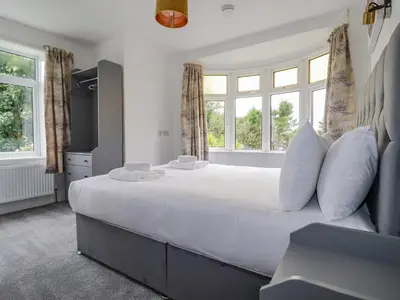 a bedroom with a large white bed with windows at Pen-Y-Thon House in Newquay