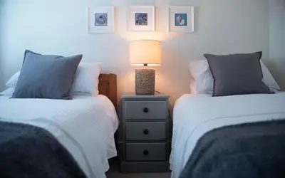 a bedroom with two beds and a lamp on a night stand at Brakestone Cottage in the heart of Port Isaac in Port Isaac