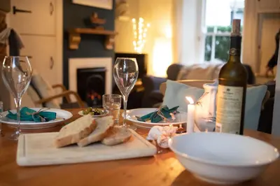 a wooden table with a bottle of wine and glasses at Brakestone Cottage in the heart of Port Isaac in Port Isaac