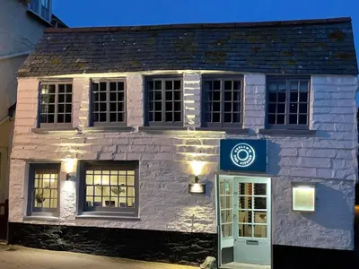 a white brick building with a blue sign on it at Brakestone Cottage in the heart of Port Isaac in Port Isaac
