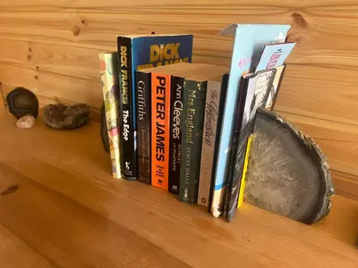 a row of books sitting on a wooden shelf at The Hobbit Hole in Zelah