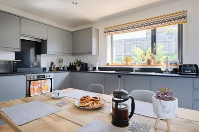 a kitchen with a table with a plate of donuts on it at Finest Retreats - Seadog in Porthleven