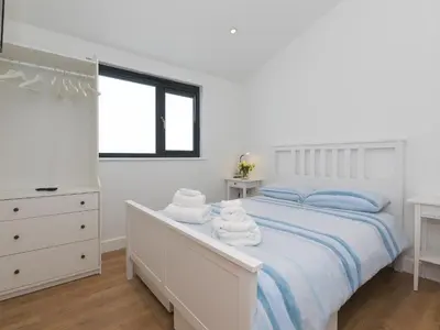 a white bedroom with a bed with towels on it at The Sandbox in Hayle