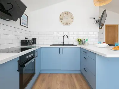 a kitchen with blue cabinets and a sink at The Sandbox in Hayle