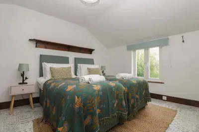 a bedroom with a bed with a green comforter at Myrtle Cottage in Hayle