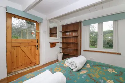 a bedroom with a bed and a wooden door at Myrtle Cottage in Hayle