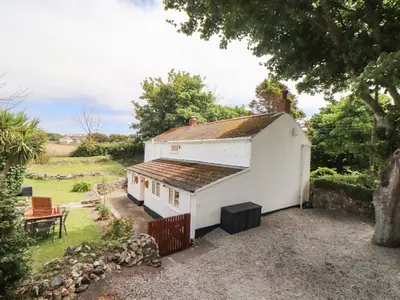 a small white house with a fence and a yard at Myrtle Cottage in Hayle