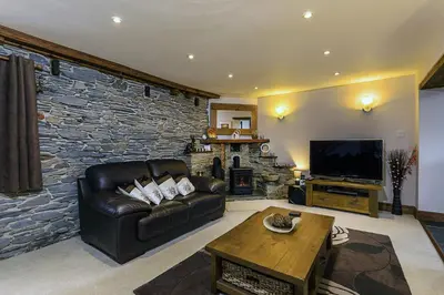 a living room with a leather couch and a tv at White Hart Cottage, Menheniot, Nr Looe in Menheniot
