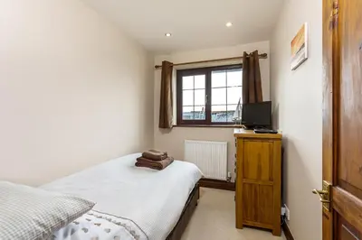 a small bedroom with a bed and a television at White Hart Cottage, Menheniot, Nr Looe in Menheniot