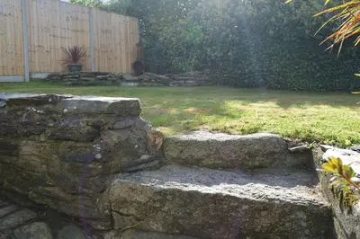 a stone retaining wall in a yard with a garden at White Hart Cottage, Menheniot, Nr Looe in Menheniot