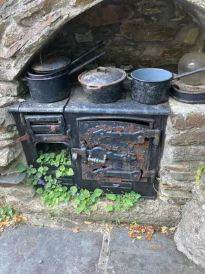 an old stone oven with pots and pans on it at Bissick Old Mill Suite in Truro