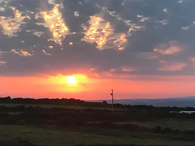 a sunset over a field with a cell phone pole at Stunning views & sunrises from Sally Saracen in St Ives