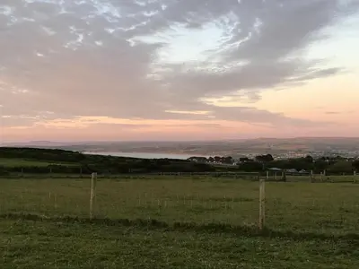 a field with a fence in the middle of a field at Stunning views & sunrises from Sally Saracen in St Ives