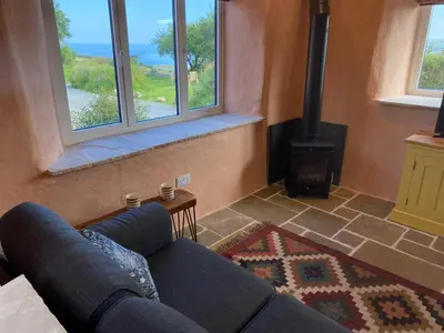 a living room with a couch and a stove at Polrunny Farm sea view Blueberry Cottage with log burner in Boscastle