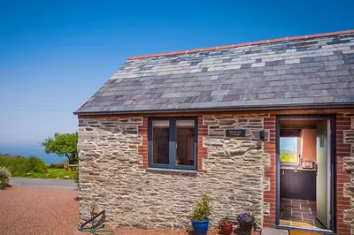a stone cottage with a window and a door at Polrunny Farm sea view Blueberry Cottage with log burner in Boscastle