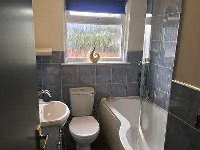 a bathroom with a toilet and a sink and a window at Seymour Apartment - Looe in Looe