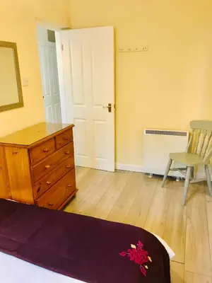 a bedroom with a wooden dresser and a chair at Towan Beach Holiday Flat in Newquay