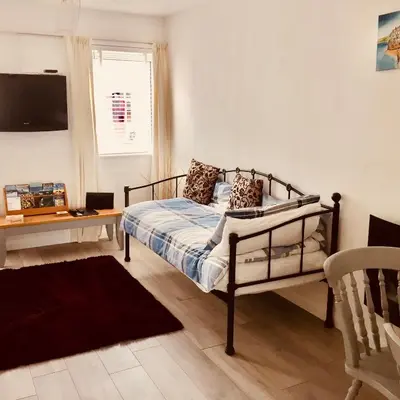 a bedroom with a bed and a table and a window at Towan Beach Holiday Flat in Newquay