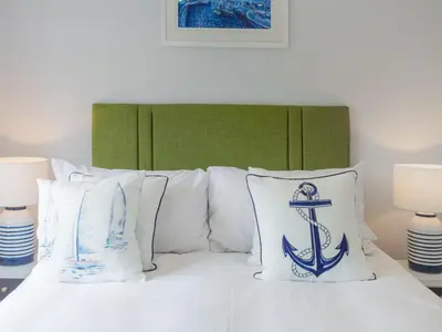 a bed with blue and white pillows on it at Holiday Home Sea Echo by Interhome in St Austell