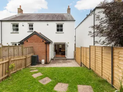 a white house with a wooden fence and a yard at Holiday Home Sea Echo by Interhome in St Austell