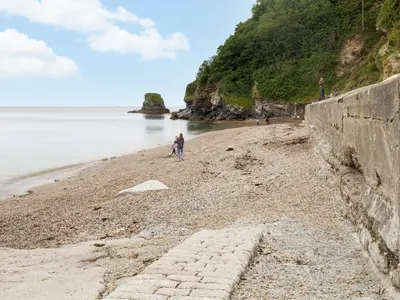 a beach with a retaining wall and people on the beach at Holiday Home Sea Echo by Interhome in St Austell