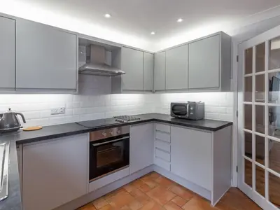 a kitchen with white cabinets and a microwave at Holiday Home Sea Echo by Interhome in St Austell