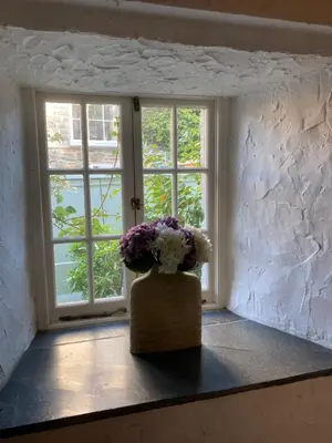 a vase of flowers sitting in front of a window at Bissick Old Mill in Truro