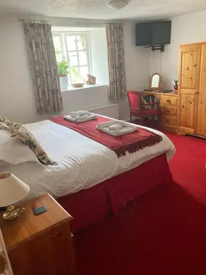 a bedroom with a bed and a desk and a window at Bissick Old Mill in Truro
