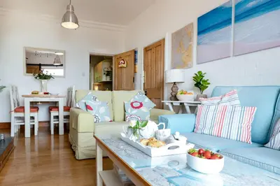 a living room with blue couches and a table at The Old Coastguard Station in Falmouth